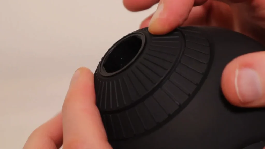 Close up of two hands opening a ribbed, black spherical object.